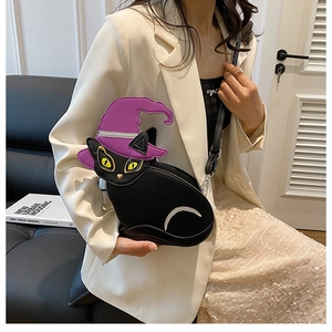 Detail view of black cat-shaped crossbody bag with a purple witch hat and crescent moon decor