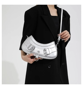 Detail of silver crescent shoulder bag with metallic texture and buckle decor