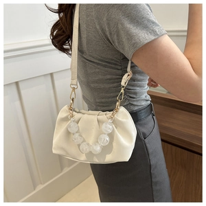Detail of creamy white pleated cloud bag with stylish frosted bead handle shown on model