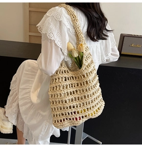 Detail view of beige woven tote bag with large hollow crochet pattern and wide straps