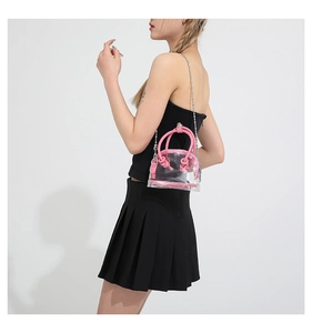 Détail du mini sac bandoulière rose en PVC avec chaîne argentée porté par un mannequin