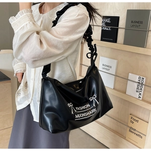 Close-up of black PU leather handbag featuring white bow print and ruched strap detail