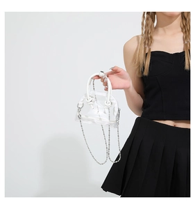 Vue détaillée d'un mini sac à main en PVC transparent avec poignée blanche et fine chaîne à billes