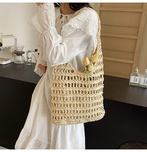 Detail of hand-woven straw mesh tote bag with large openwork pattern and tulip accents