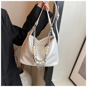 Dettaglio della borsa a mezzaluna bianco perlato con catena decorativa in perle e metallo