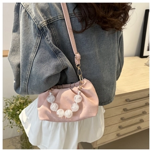 Pink pleated cloud crossbody bag with marble beaded chain shown in lifestyle setting
