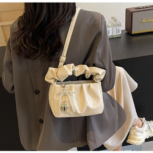 Detailed close-up of cream PU crossbody bag with pleated texture and pearl bow charm