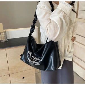 Close-up of black PU leather bag with white fashion print and pleated scrunchie strap