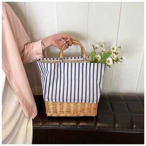 Detail of a straw tote bag with blue white stripes and circular wooden handles