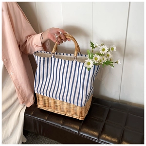Detail of striped canvas and woven straw bucket bag with circular wooden handles
