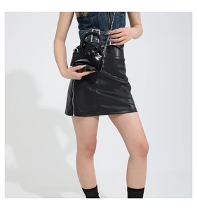 Détail d'un mini sac à main en cuir verni noir avec bandoulière chaîne sur un mannequin