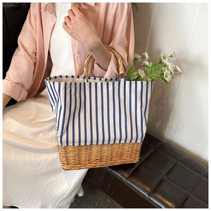 Detailed close-up of woven straw bag with blue striped canvas and bamboo handle