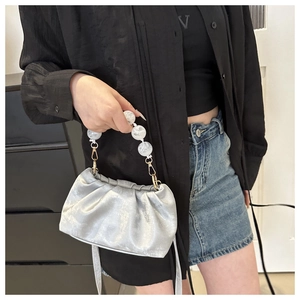 Detail of silver metallic pleated cloud bag with marble bead handle and gold hardware