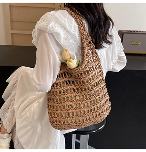 Detail of hollow-out hand-woven straw shoulder bag in coffee brown with inner fabric lining