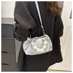 Detail of silver pleated cloud bag with white pearl handle and gold metallic hooks