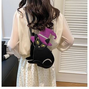 Detail of a black PU leather witch cat crossbody bag worn over a shoulder on a model