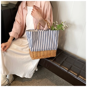 Detail of hand-woven straw base and striped canvas bag with vintage bamboo top handle