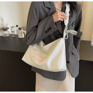 Detail of cream PU crossbody bag with ruffled strap and pink bow on grey blazer