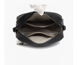Interior view of black pebbled leather crossbody bag with grey herringbone lining layers