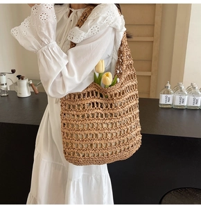 Detail of trendy woven straw tote bag with cutout pattern on a summer dress model