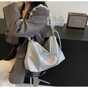 Detail of silver metallic PU shoulder bag with pink bow and pleated strap design