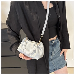 Detail of silver metallic dumpling bag featuring chunky clear bead handle and pleated texture