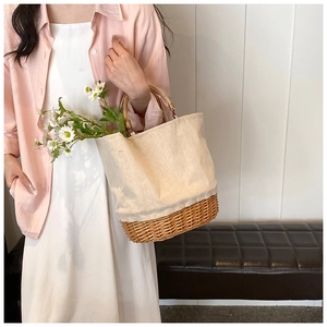 Detail of woven rattan base and canvas top of a stylish bucket bag with wooden handle