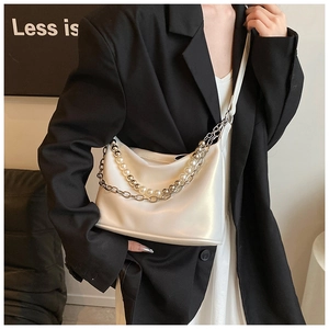 Dettaglio borsa a tracolla in pelle PU crema con perle decorative e catene metalliche