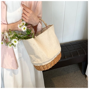Detail of straw woven tote with cream canvas trim and small daisies inside the bag