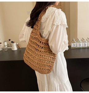 Detail of a large hand-woven straw tote bag styled with a summer dress in a cafe