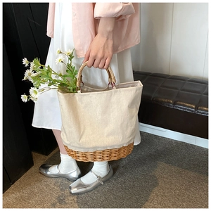 Detail of canvas and woven straw tote bag with round wooden handle and daisy flower accent