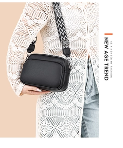 Detail of black pebbled leather crossbody bag with stylish geometric patterned wide strap