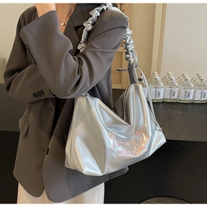Detail of silver pleated PU handbag featuring pink bow embroidery and ruffled cloud strap