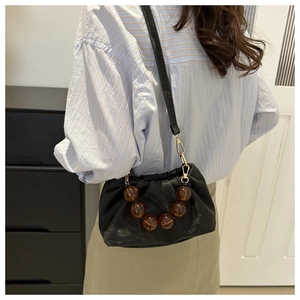 Close-up of black pleated cloud bag with amber resin beads and gold hardware details