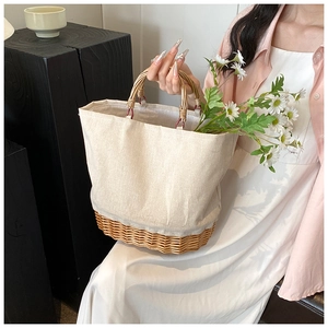 Detailed shot of woven straw handbag featuring beige canvas stitching and daisy floral decor