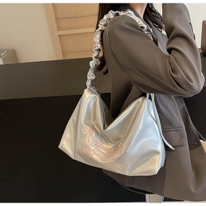 Detail of silver metallic tote bag with ruched handle and pink bow embroidery