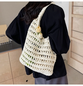 Close-up of white hand-woven straw tote bag with crochet hollow mesh and yellow tulips