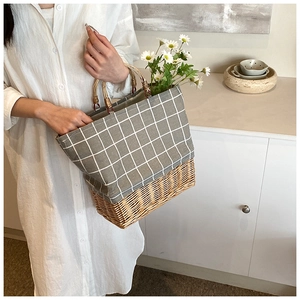 Detail of hand-woven straw tote with bamboo handles and checkered fabric texture