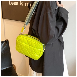 Detail of quilted bright yellow crossbody bag with black and white wavy shoulder strap