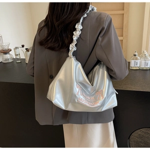 Detail view of metallic silver PU tote bag with pink embroidered bow and pleated shoulder strap