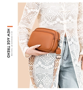 Detail view of brown pebbled leather crossbody bag with geometric pattern wide strap