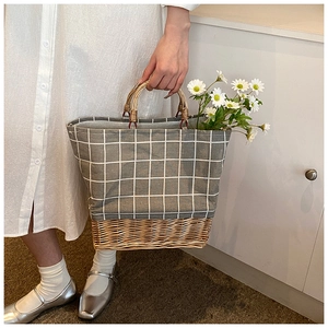 Detail of grey checkered canvas tote bag with woven straw base and round wooden handle