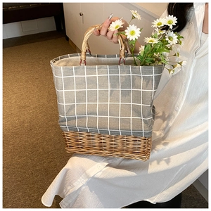 Detail showing grey plaid canvas and woven rattan base of the trendy bucket handbag