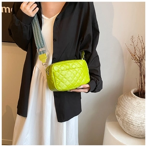 Detail of lime green quilted crossbody bag with stylish wide woven shoulder strap