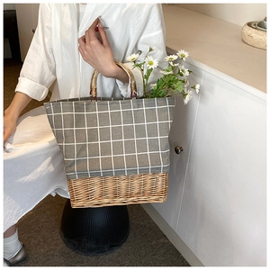 Detail view of woven straw tote bag featuring grey checkered canvas and bamboo handle