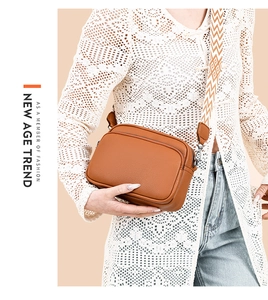 Detail of orange cross-body camera bag with stylish geometric woven shoulder strap