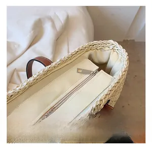 Détail du sac cabas en paille tissée avec fermeture éclair en argent et poignées en cuir