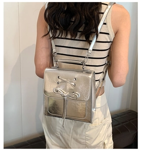 Close-up of metallic silver PU backpack with decorative bow detail and flap closure