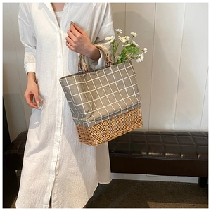 Detail of woven straw handbag featuring grey grid canvas and round wooden handles