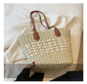 Détail de la texture du sac cabas en paille kaki et des anses d'épaule en cuir marron